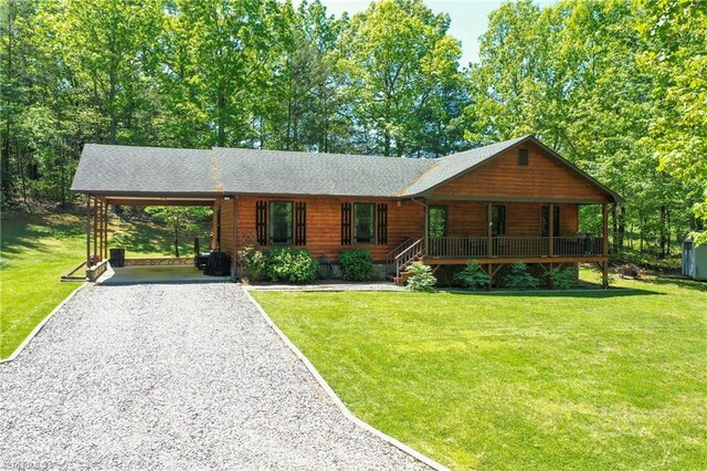 view of front of home with covered porch, gravel driveway, a front yard, and an attached carport