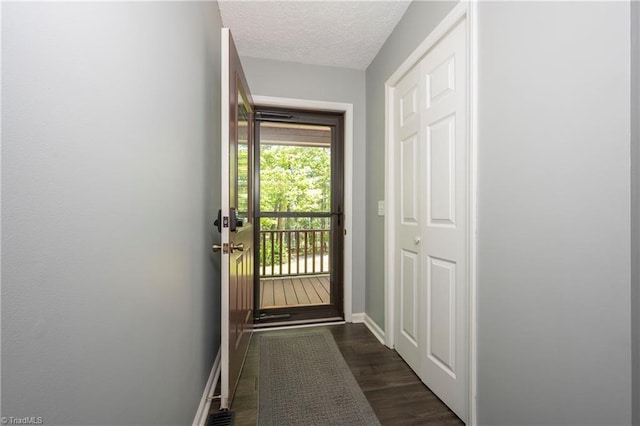 entryway featuring a textured ceiling, baseboards, and dark wood-type flooring