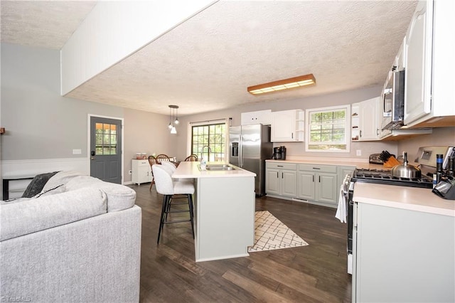 kitchen featuring dark wood-type flooring, a textured ceiling, a breakfast bar, and stainless steel appliances