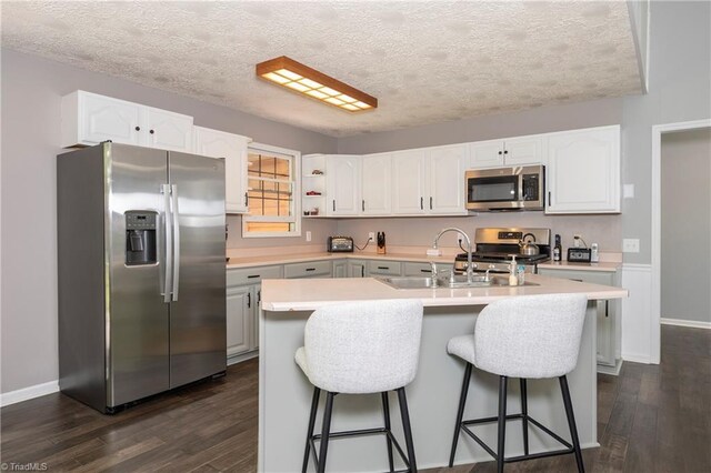 kitchen featuring dark wood-type flooring, a sink, appliances with stainless steel finishes, and light countertops