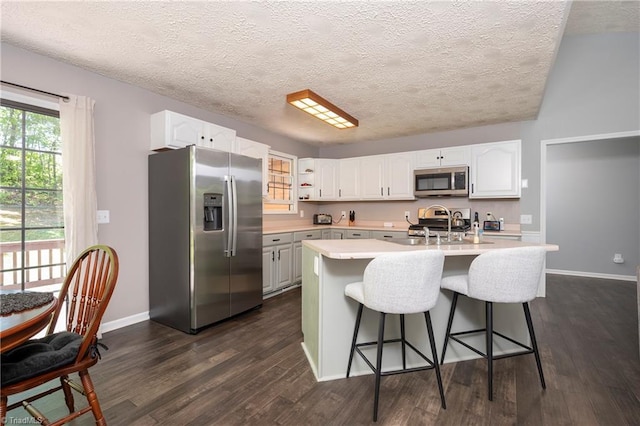 kitchen featuring light countertops, a kitchen bar, white cabinets, and stainless steel appliances