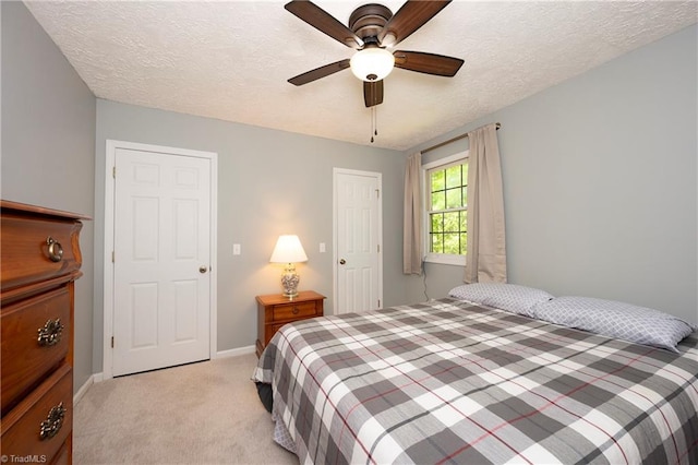 bedroom featuring baseboards, ceiling fan, a textured ceiling, and light colored carpet