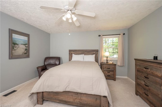 bedroom featuring visible vents, a textured ceiling, baseboards, and light carpet