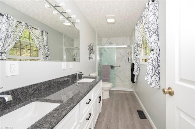 full bath featuring a textured ceiling, visible vents, a sink, toilet, and a marble finish shower