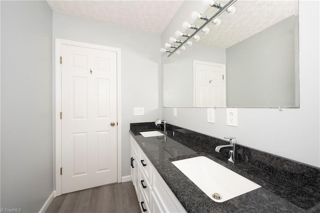 bathroom featuring a textured ceiling, a sink, and wood finished floors