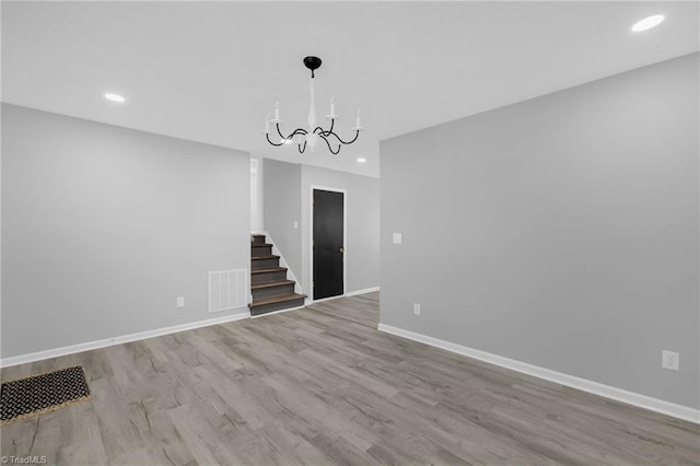 empty room featuring an inviting chandelier and light hardwood / wood-style flooring