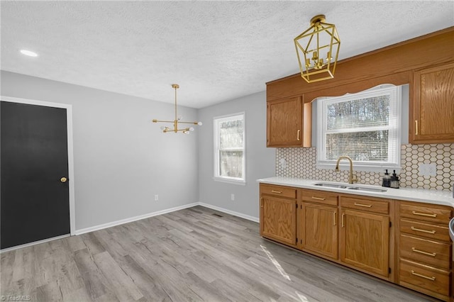 kitchen featuring sink, decorative backsplash, a notable chandelier, and hanging light fixtures