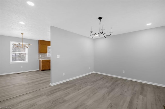 unfurnished dining area featuring light hardwood / wood-style floors and a chandelier