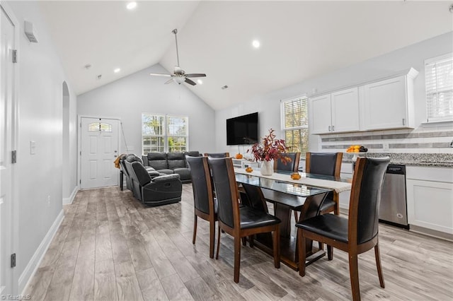 dining room featuring ceiling fan, high vaulted ceiling, and light wood-type flooring