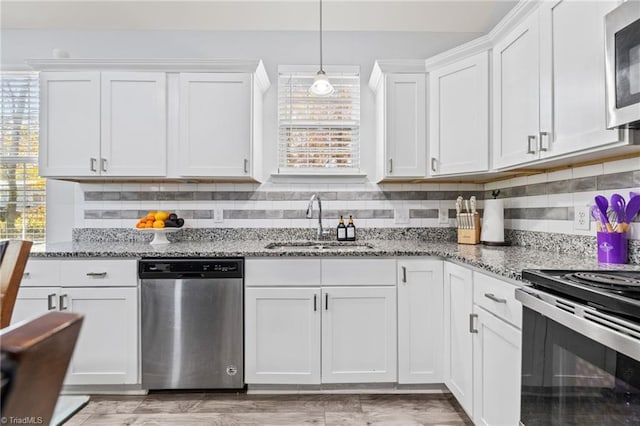 kitchen with light stone counters, white cabinetry, sink, and appliances with stainless steel finishes