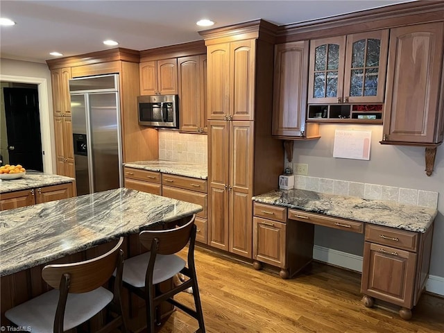 590 Knob View Dr, Winston-Salem, NC 27104 - kitchen featuring appliances with stainless steel finishes, built in desk, a kitchen breakfast bar, light wood-style floors, and backsplash