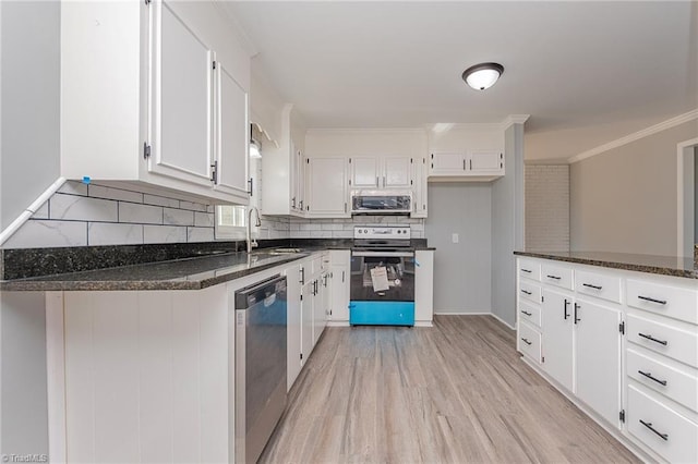 kitchen featuring appliances with stainless steel finishes, white cabinetry, dark stone counters, and sink