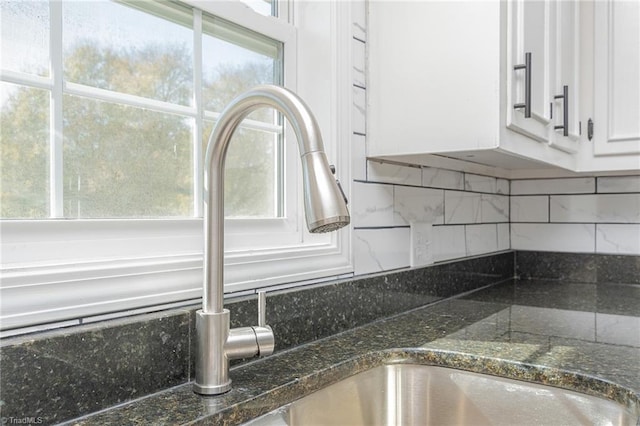 room details featuring dark stone countertops, decorative backsplash, and white cabinets