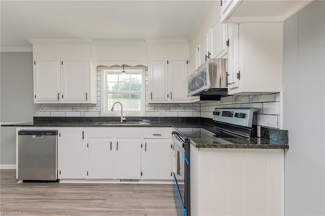 kitchen featuring appliances with stainless steel finishes, light hardwood / wood-style floors, white cabinetry, and dark stone countertops