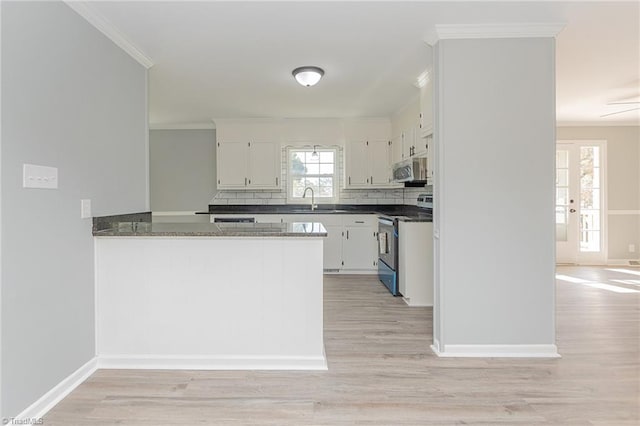 kitchen with kitchen peninsula, appliances with stainless steel finishes, light wood-type flooring, sink, and white cabinetry