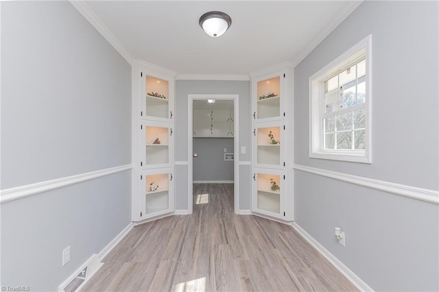 interior space with built in shelves, crown molding, and light wood-type flooring