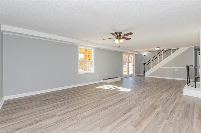 unfurnished living room featuring a textured ceiling, light wood-type flooring, and ceiling fan