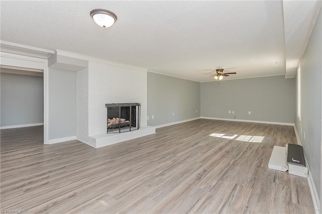 unfurnished living room featuring ceiling fan, light hardwood / wood-style floors, ornamental molding, and a textured ceiling