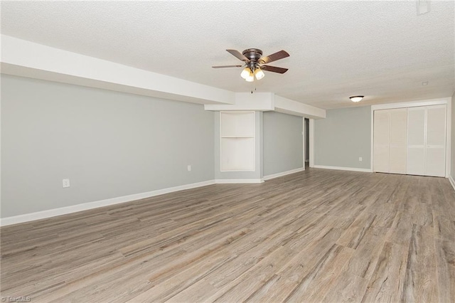 basement featuring ceiling fan, light hardwood / wood-style floors, and a textured ceiling