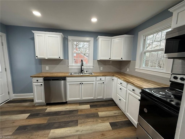 kitchen featuring dark wood-style floors, a sink, appliances with stainless steel finishes, wood counters, and backsplash