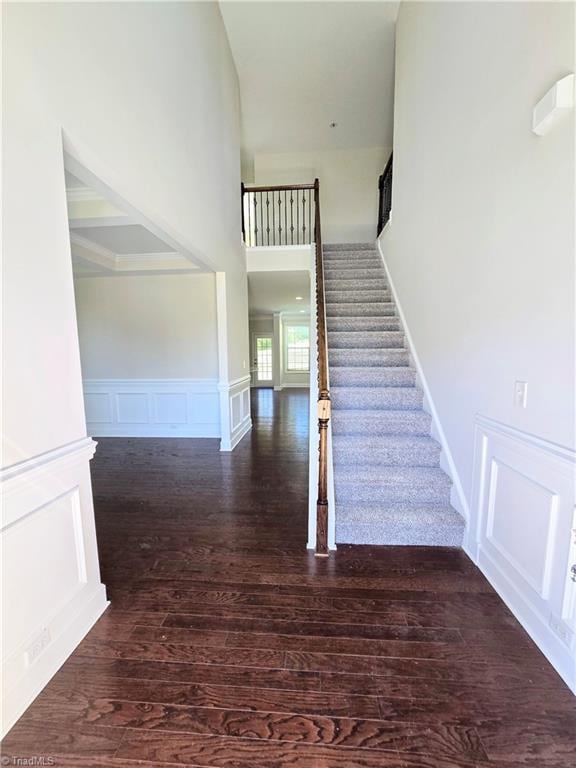 staircase featuring wood-type flooring and a high ceiling