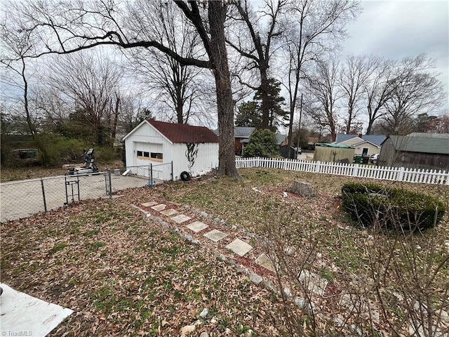 view of yard with a fenced front yard, a detached garage, and an outbuilding