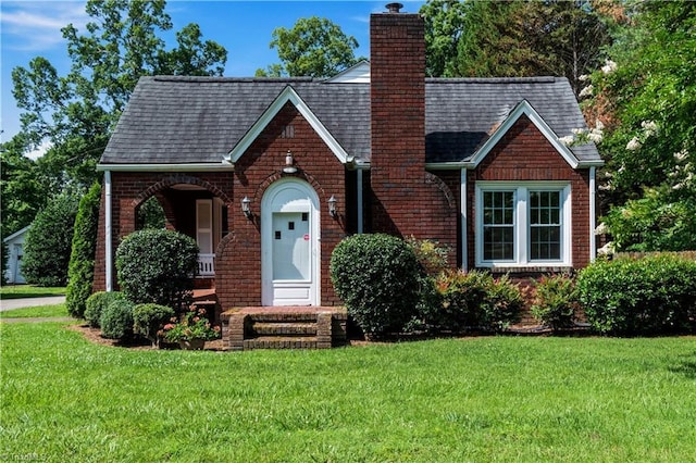 7090 Reynolda Rd, Pfafftown, NC 27040 - tudor house with brick siding, a front lawn, a chimney, and a shingled roof