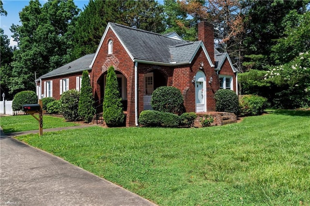 7090 Reynolda Rd, Pfafftown, NC 27040 - tudor house with brick siding, roof with shingles, a front yard, and a chimney