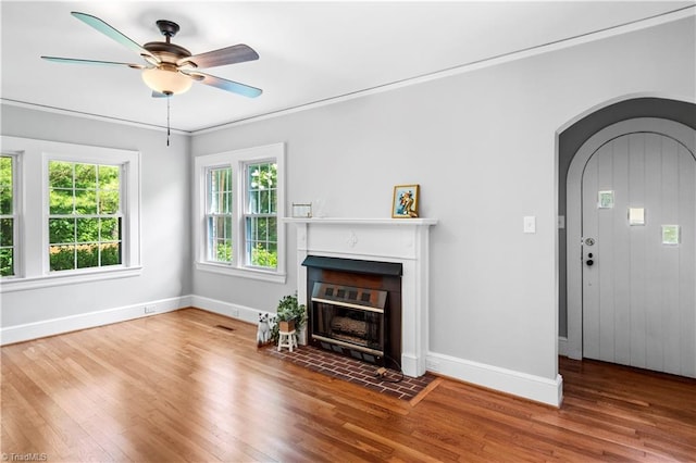 7090 Reynolda Rd, Pfafftown, NC 27040 - unfurnished living room with wood finished floors, arched walkways, ceiling fan, a fireplace with flush hearth, and ornamental molding
