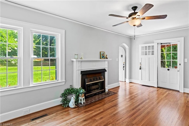 7090 Reynolda Rd, Pfafftown, NC 27040 - living area with arched walkways, wood finished floors, a fireplace with flush hearth, a ceiling fan, and ornamental molding