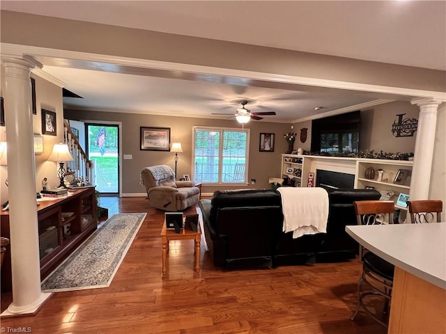 living room featuring decorative columns, crown molding, ceiling fan, and dark hardwood / wood-style floors