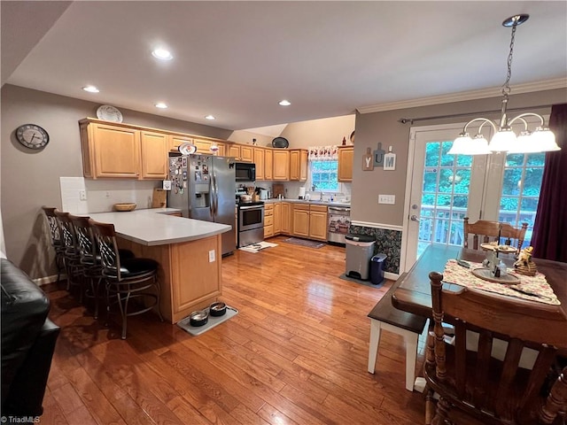 kitchen with light wood-type flooring, crown molding, stainless steel appliances, kitchen peninsula, and a breakfast bar area