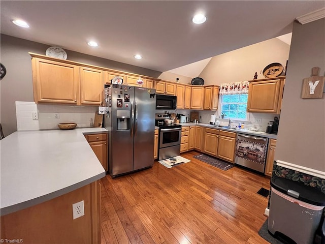 kitchen with light wood-type flooring, lofted ceiling, stainless steel appliances, and sink