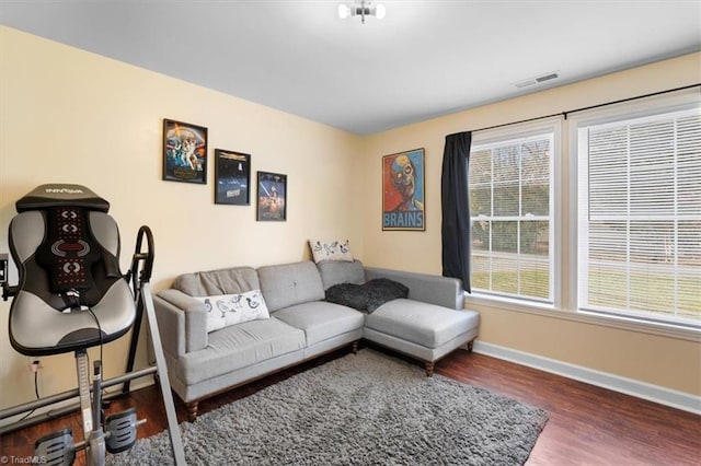 living room featuring visible vents, baseboards, and wood finished floors