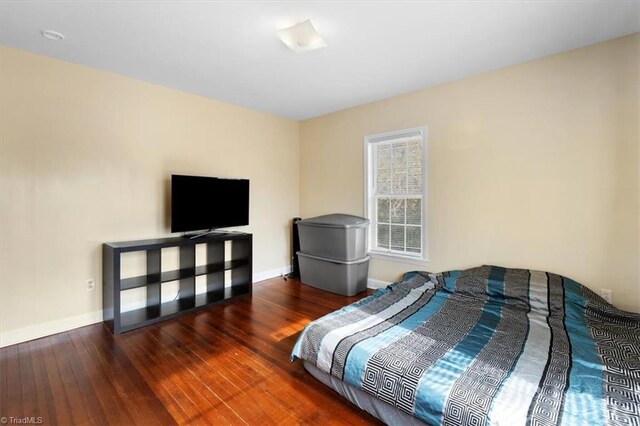 bedroom with baseboards and hardwood / wood-style flooring