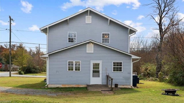 rear view of house featuring an outdoor fire pit and a lawn