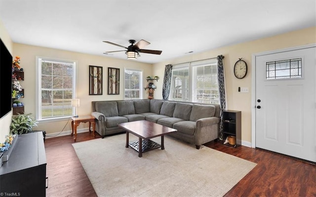 living room featuring dark wood-style floors, baseboards, and a healthy amount of sunlight