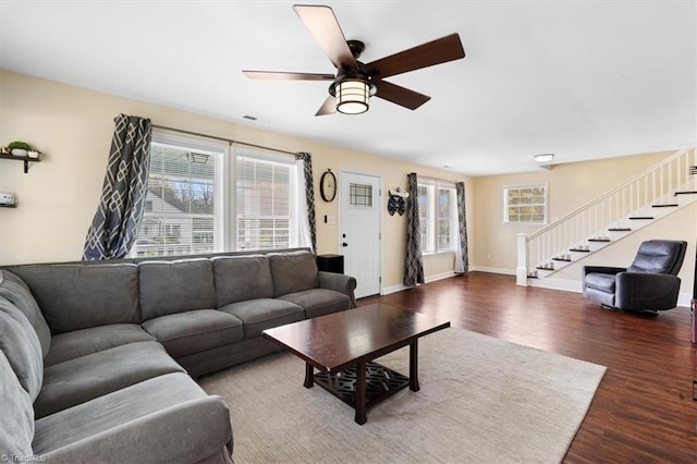 living area with ceiling fan, stairway, baseboards, and wood finished floors