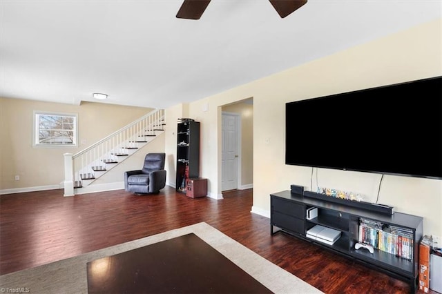 living area with a ceiling fan, baseboards, stairway, and wood finished floors