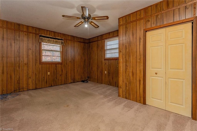 carpeted spare room with ceiling fan and wooden walls