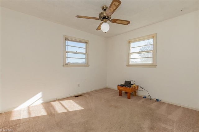 spare room with light carpet, ceiling fan, and a healthy amount of sunlight