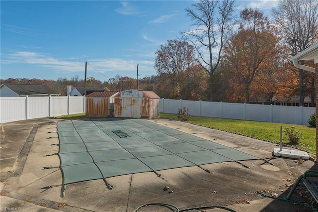 view of pool with a lawn, a patio area, and a storage shed