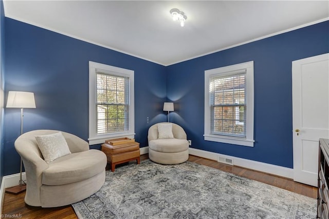 living area featuring wood-type flooring and ornamental molding