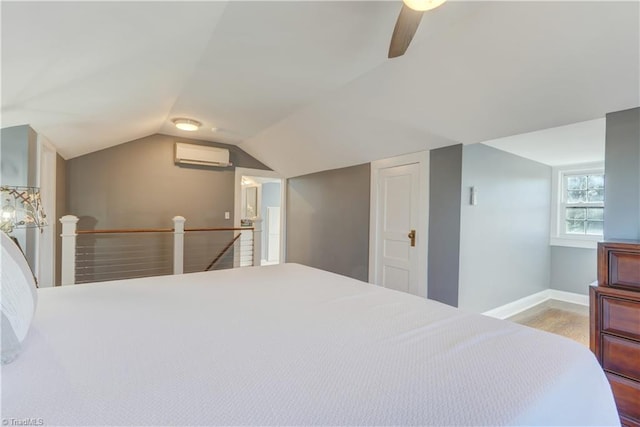 bedroom featuring ceiling fan, light hardwood / wood-style floors, a wall mounted AC, and vaulted ceiling