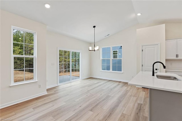 unfurnished dining area featuring a chandelier, lofted ceiling, light hardwood / wood-style floors, and sink