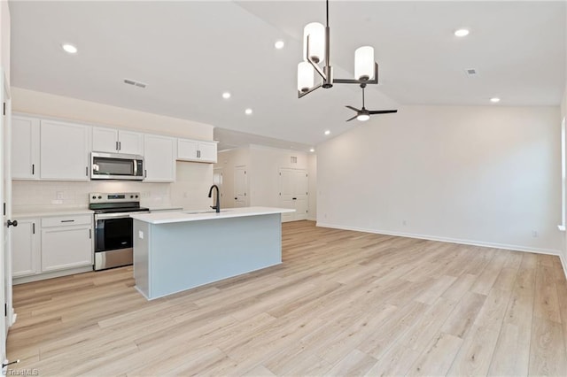 kitchen with decorative light fixtures, stainless steel appliances, an island with sink, and white cabinets