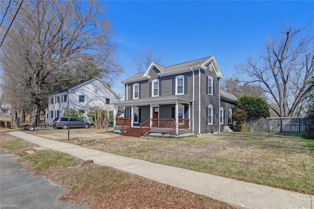 view of front facade featuring covered porch, a front lawn, and fence