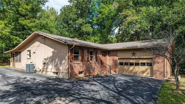 ranch-style home featuring central AC unit and a garage