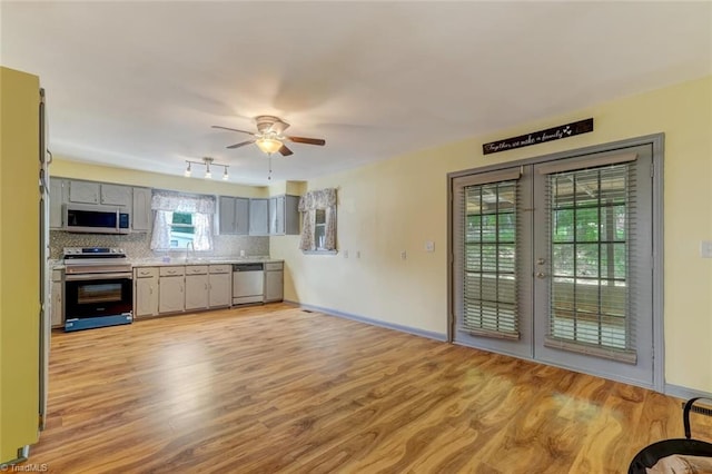 kitchen featuring appliances with stainless steel finishes, gray cabinetry, light hardwood / wood-style floors, tasteful backsplash, and ceiling fan