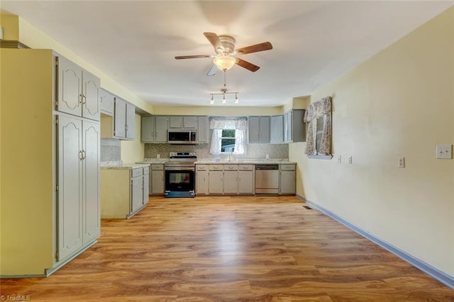 kitchen with appliances with stainless steel finishes, decorative backsplash, light hardwood / wood-style floors, and sink